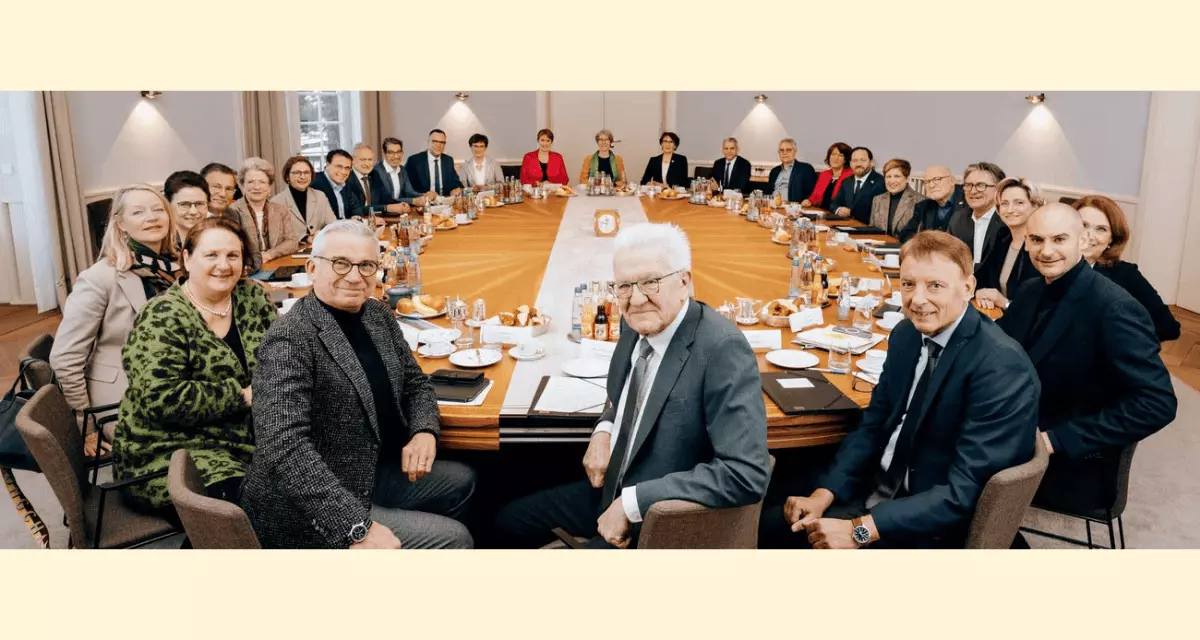 Foto der Landesregierung. Alle sitzen an einem ovalen Tisch. Vorne Ministerpäsident Kretschmann in der Mitte.