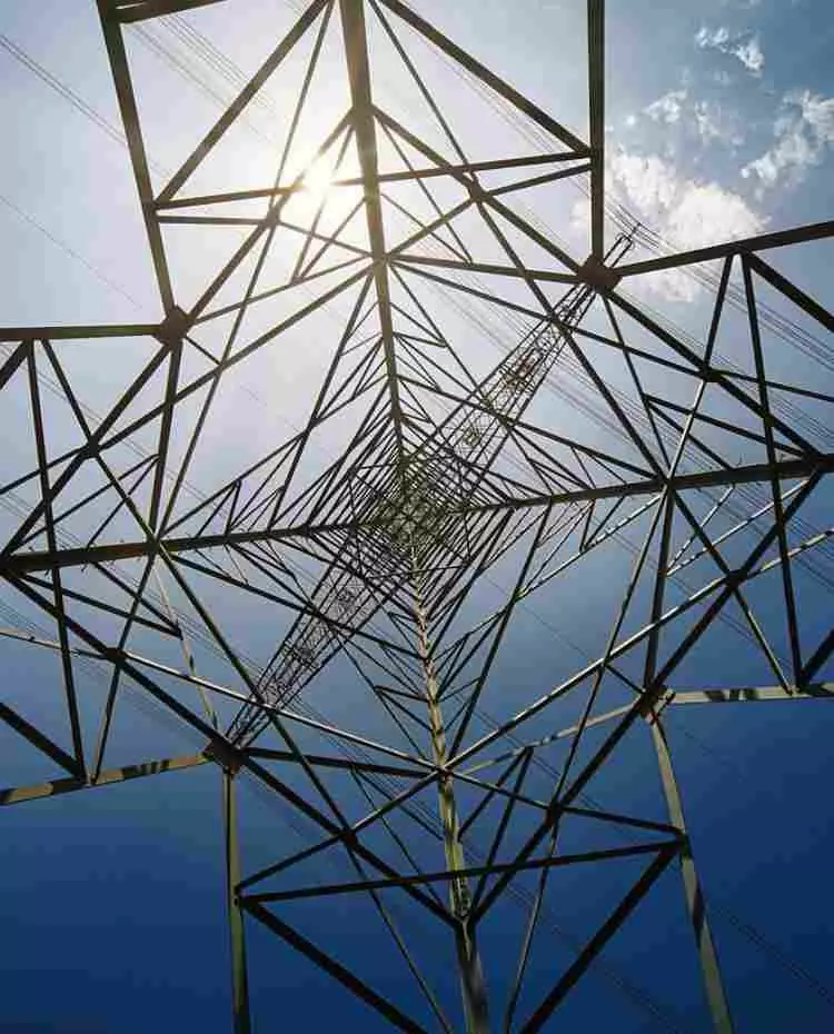 Blick in einen Strommast von innen nach oben gegen den blauen Himmel.