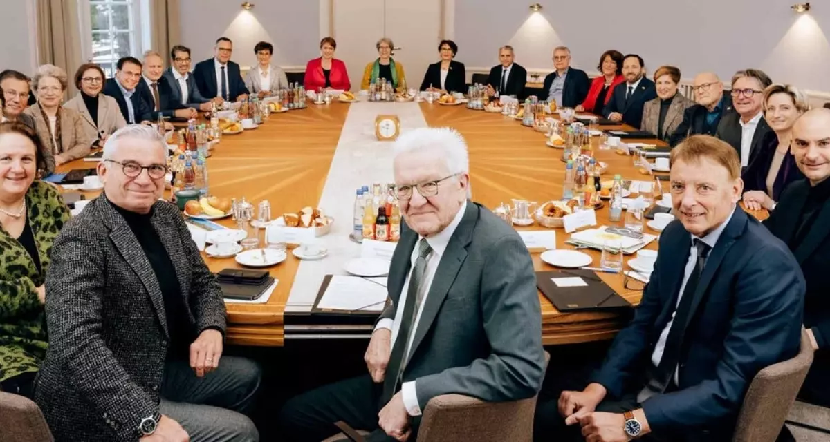 Kabinett Baden-Württemberg | Landesregierung Baden-Württemberg Alle Mitglieder des Kabinetts Baden-Württemberg sitzen an einem runden Tisch und schauen in die Kamera.