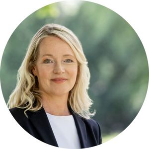 Potraitfoto von Thekla Walker. Sie hat schulterlanges blondes Haar, trägt ein weißes T-Shirt und einen schwarzen Blazer. Der Hintergrund ist grün.