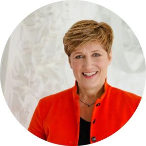 Potrait von Nicole Ravazi. Sie trägt einen roten Blazer und eine Kurzhaarfrisur und lächelt leicht in die Kamera.