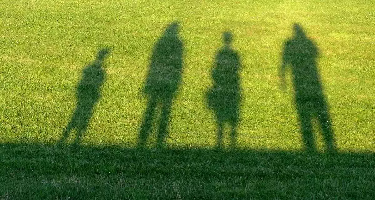 Symbolbild Familie. Foto: Pixabay via Canva | Monsterkoi Die Schatten von vier Personen auf einer Wiese.