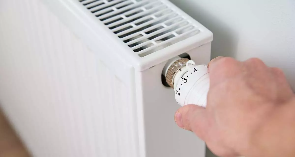 Symbolbild Wärme. Foto: Canva | aliaksandrbarysenka Eine Hand dreht ein Heizungsthermostat.